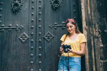 Smiling female tourist with photo camera standing near old building