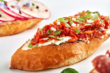 Assorted delicious bruschetta with tomatoes, strawberries, avocado, radish, Camembert and prosciutto. Close-up, top view, on a white background