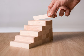Male hand stacking wooden blocks. Business development and growth concept