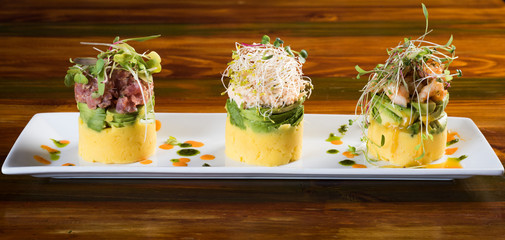 Traditional Peruvian dish called Causa made of mashed potato with aji hot pepper and lime juice and filled with vegetables corn, peas, carrots and mayonnaise Selective Focus, Focus on front