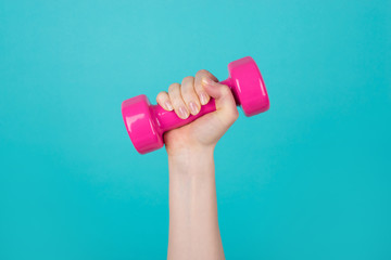 Working out concept. Cropped photo of sportive woman holding pink dumbbell isolated on blue teal turquoise background
