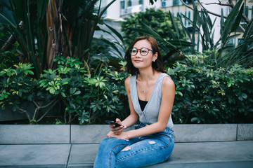 Asian hipster sitting in park with phone