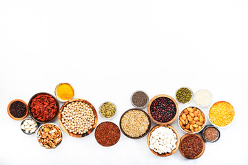 Various superfoods, legumes, cereals, nuts, seeds in bowls on white background. Superfood as chia, spirulina, beans, goji berries, quinoa, turmeric, mung bean, buckwheat, lentils, flax seed