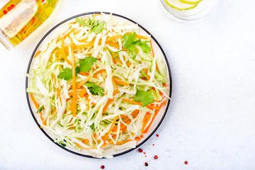 White cabbage salad coleslaw with carrot on white kitchen table background. Top view, copy space