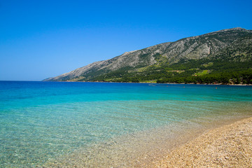 Beautiful beach on the Zlatny Rat peninsula near Bol on the island of Brac in Croatia - Turquoise transparent waters of the Adriatic Sea in summer