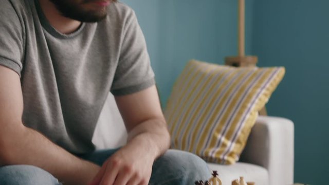 Young man is sick and tired with aimless activities, playing chess in self-isolation, struggling from the lack of live communication with close people, Slow motion.
