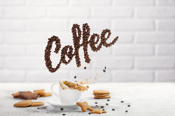 Coffe splash from cup with cookies and coffee beans spelling the word Coffee