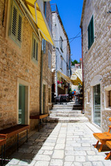 Fototapeta na wymiar Narrow stone-paved steep street in the village of Hvar on the eponymous Croatian island