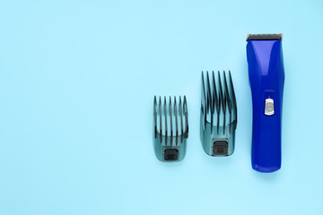 Blue hair clipper with two attachments on a blue background. Space for text. Selective focus. Tools for working as a hairdresser. Copy space