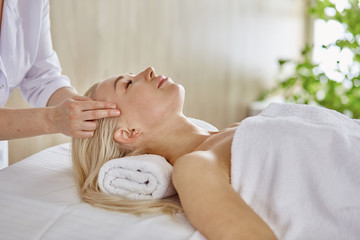 Fototapeta na wymiar Beautiful woman with closed eyes getting a massage in the spa salon