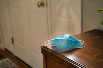 Mask on table looking towards door. Using mask as protecting from coronavirus to flatten the curve
