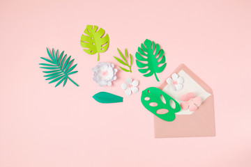 Paper tropical leaves and flowers over pink pastel background. Summer exotic vacation, greeting card mockup. Top view