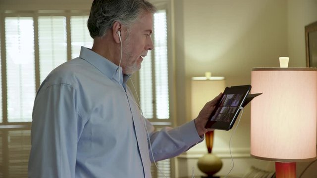 A mature man who is part a virtual meeting with his coworkers via a tablet pc part of the new reality in 2020 of working from home due to the pandemic.