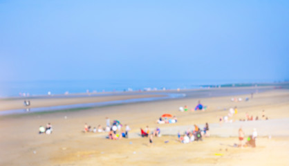 Fototapeta premium Landscape of blurry crowd of people sitting and lying down on the sand beach, Blurred image of People enjoy swimming in a sunny day at tropical beach, Summer holiday concept.