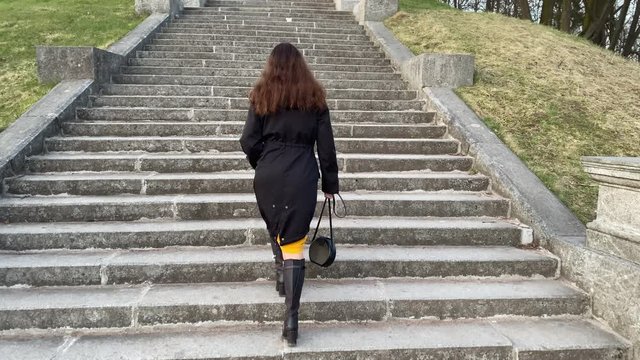 Rear view of woman walking up the stone steps in the park, Marienthal pond and staircase in Pavlovsk park, Saint Petersburg, Russia.