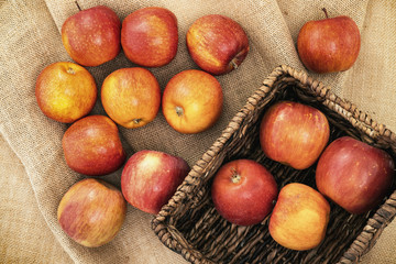 Fresh red apples in wicker basket on rustic background, close up, view from above