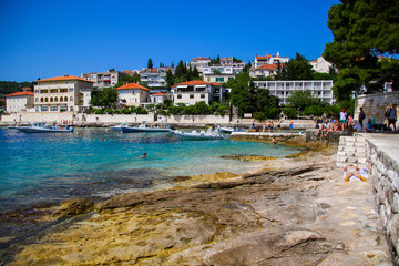 Tourists swimming in the Adriatic Sea near the Hvar city harbor on Hvar island in Croatia - Idyllic setting with turquoise waters and sunny warm weather in summer for the holidays