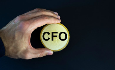 CFO letters or Chief Financial Officer on a wooden circle held by a man, black background.