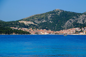 Fototapeta na wymiar Hvar island from the distance - View of the old port and the Spanish fortress of Hvar city from a boat in the Adriatic Sea