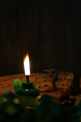 Oil lamp with flaming fire on woven tray with ketupat ornaments
