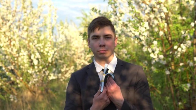 A businessman stands in the garden and sniffs dollar bills and waves them. It became hot men in a suit in nature.