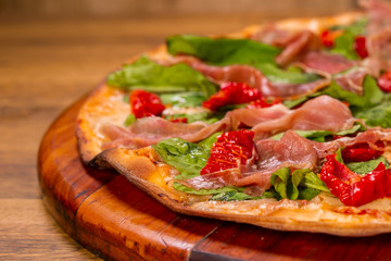 pizza with arugula with sun-dried tomatoes and parma ham on wooden background