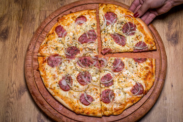 Hand holding Pepperoni pizza in Brazil is called Pizza de calabresa. close up