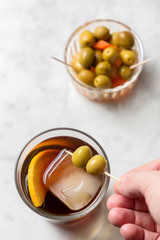 Man's hand picking olives from red vermouth. Top view