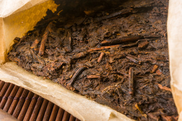 Chinese pressed PU-erh tea on wrapping paper on a bamboo Mat, close-up, macro