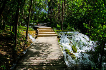 Wooden path built over the streaming waters of Krka National Park in Croatia - Hike through the forest along the flowing river among the waterfalls