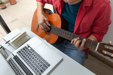 Man receiving online guitar lessons at home