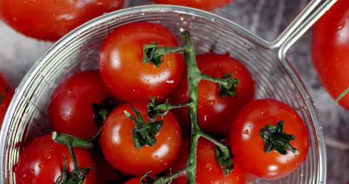 Tomatoes on a branch in colander slowly rotate.