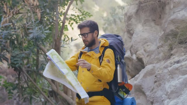 Traveler man with paper map walking in mountain area