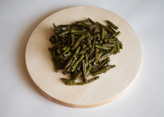 Young pickled fern on the round wooden board. Sliced for further cooking