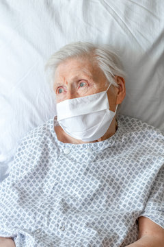 Portrait de personne &acirc;g&eacute;e sur lit d'h&ocirc;pital, avec masque blanc