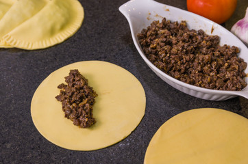 Preparation of Brazilian pastry (pastel), traditional dish of Brazilian cuisine in a dish on a black granite background.