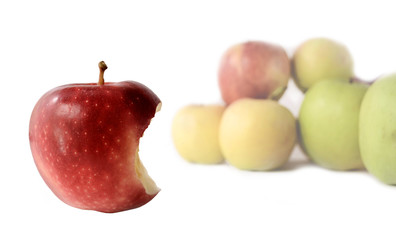 One red apple with a bitten side and several yellow apples on a white background