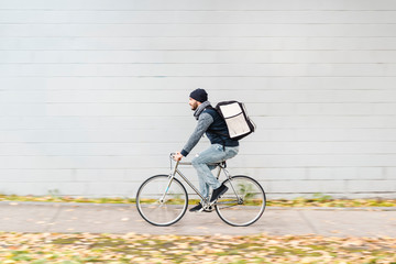 Food delivery rider in motion by a white background wall perfect for copy writing
