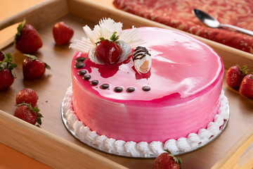 Strawberry mouse cake with a chocolate chip topping with a strawberry and grated white chocolate topping, nice strawberry colored cake