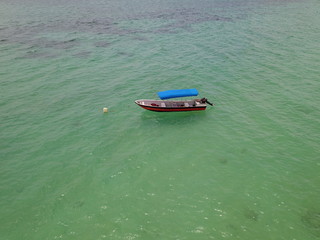 Aerial view of a boat with a blue roof in the middle of the sea in Playa Blanca, Baru Island, Colombia