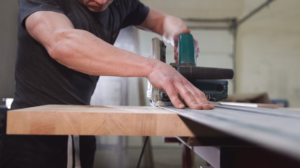 Carpenter hand on wooden board. Cutter machine with circular saw in action.