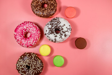 Tasty donuts and macaroons on pink background. Top view