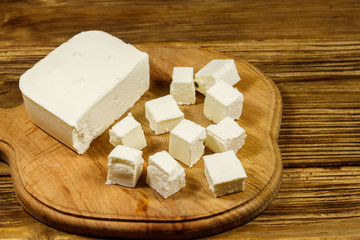 Feta cheese on cutting board on a wooden table