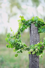 Wreath from green birch tree branches on summer rustic landscape. Young birch leaves in wreath....