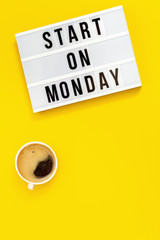 Text "start on monday" on lightbox and cup of coffee. Сoncept of new beginnings. Start of working week. Top view on yellow background.