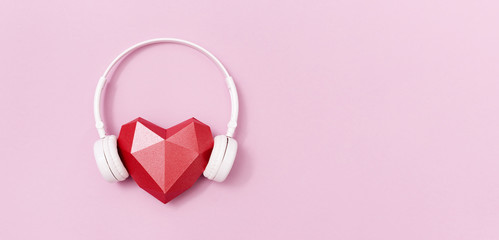 Red polygonal paper heart shape in white headphones. Music concept. Dj Headset. Minimal style. Banner with copy space.