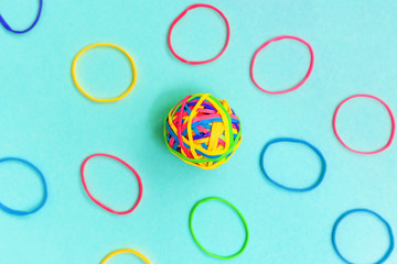 Ball or knot of thin multicolored elastic bands on plain background.