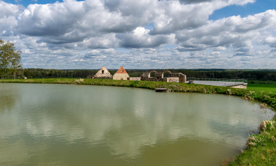 Naklejka na ściany i meble landscape with a small pond and ancient buildings on its shore, gorgeous cumulus clouds
