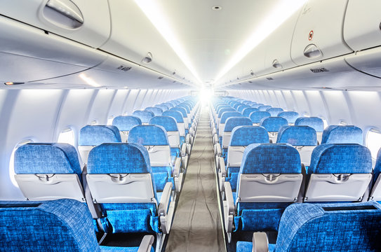 modern airplane cabin interior with empty economy class seats. Wide back side inside view of jet plane passenger compartment. Aircraft transportation background. Air travel concept