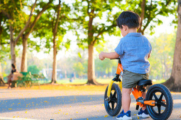 Adorable young boy riding bikes in the city park on asphalt road
